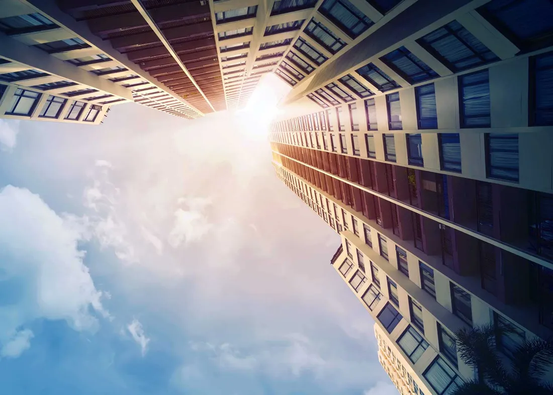 Looking up toward the light between commercial buildings
